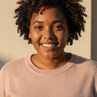 Body-positive size queen community member Maya with natural curls and a warm smile